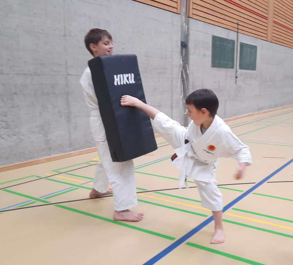Kai mit einem Sidekick (Yoko-Geri) wie aus dem Lehrbuch. Auch mit den Karate-Kindern wird mit Schlagpolster trainiert.