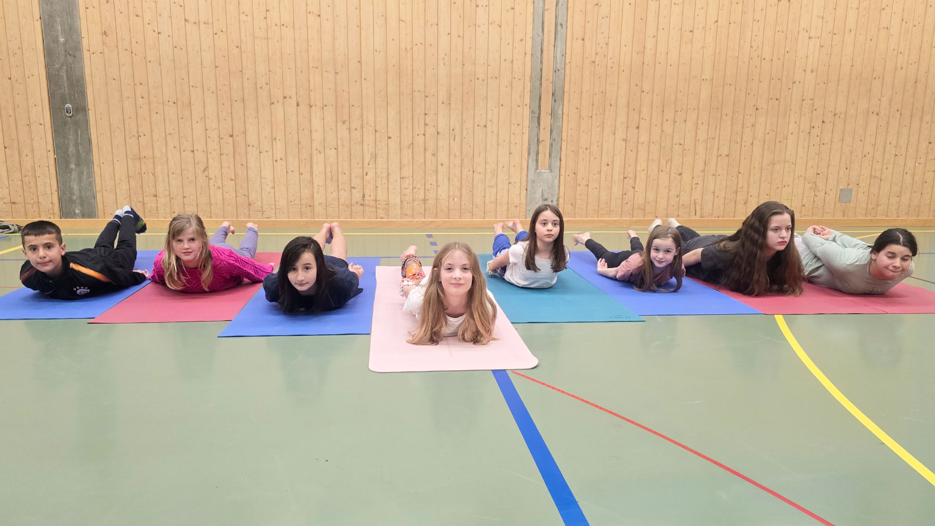 Kinder-Yoga an der Kampfsportschule Aarau. Die Kinder üben eine Variante von Bujangasana, der Schlange.
